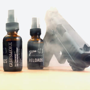 Two bottles of Gunsmoke Reload Spray next to a smoking handgun.