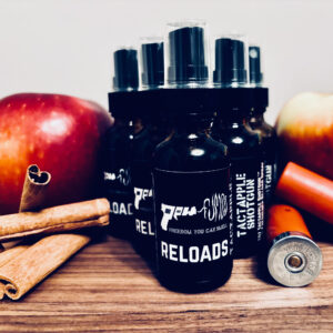 Five bottles of Tactapple Shotgun Reload Spray next to cinnamon sticks, apples, and shotgun shells